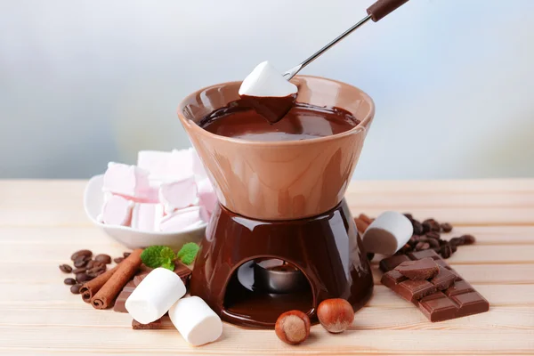 Chocolate fondue with marshmallow candies, on wooden table, on light background — Stock Photo, Image