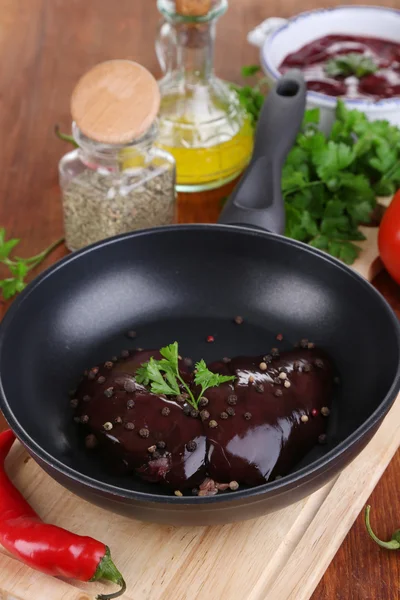 Hígado crudo en sartén con especias y condimentos en primer plano de mesa de madera —  Fotos de Stock