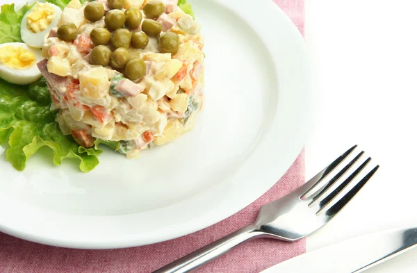 Salada tradicional russa Olivier em prato branco, em guardanapo de cor, isolado em branco — Fotografia de Stock