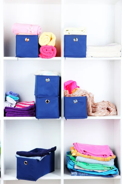 Cajas textiles azules con toallas y ropa en estantes blancos — Foto de Stock