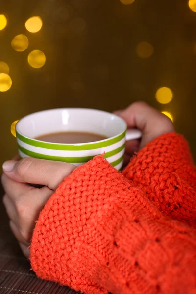 Mani che tengono tazza di bevanda calda, primo piano, su sfondo luminoso — Foto Stock