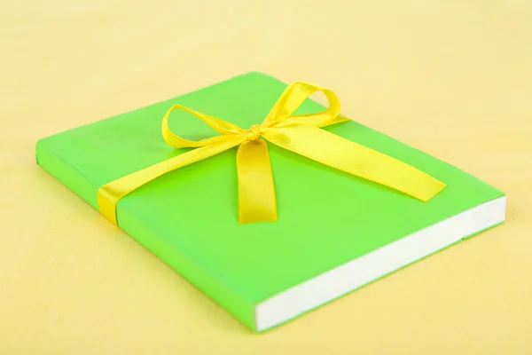 Book wrapped with color ribbon, on color background — Stock Photo, Image