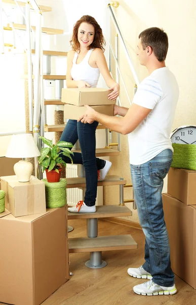 Young couple with boxes in new home on staircase — Stock Photo, Image