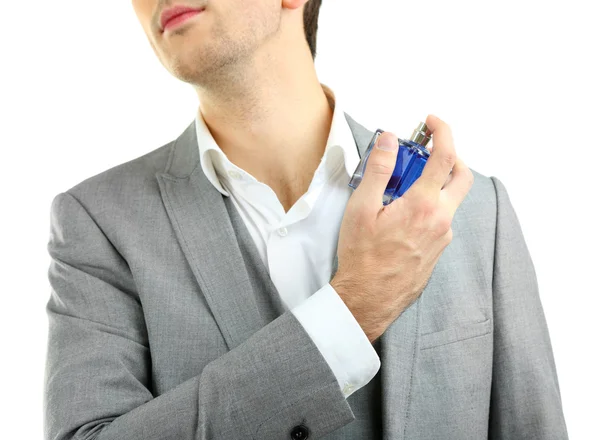 Pohledný mladý muž pomocí parfém izolovaných na bílém — Stock fotografie