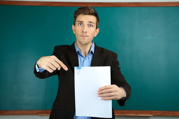 Jonge leraar in de buurt van schoolbord in school klas — Stockfoto