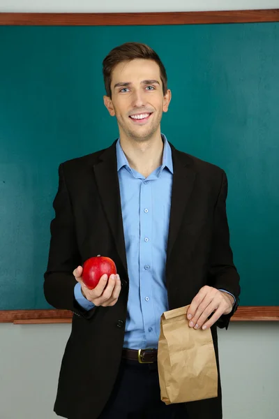 Молодий вчитель з шкільним обідом біля крейди в шкільному класі — стокове фото