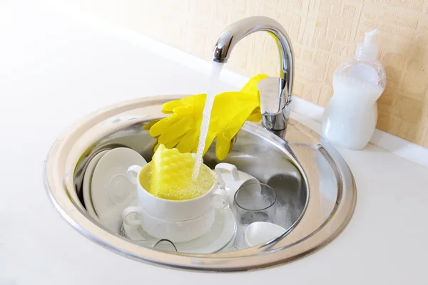 Stack of dishes soaking in kitchen sink — Stock Photo, Image