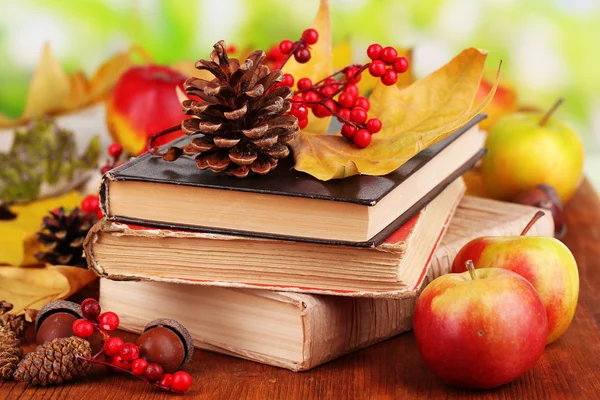 Books and autumn leaves on wooden table on natural background — Stock Photo, Image