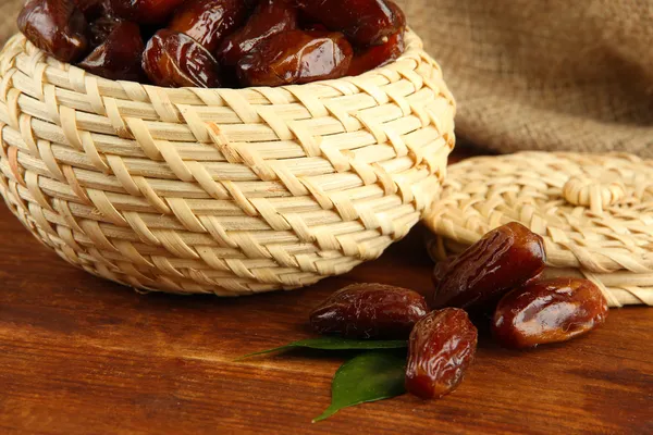 Dried dates in basket on table on sackcloth background — Stock Photo, Image