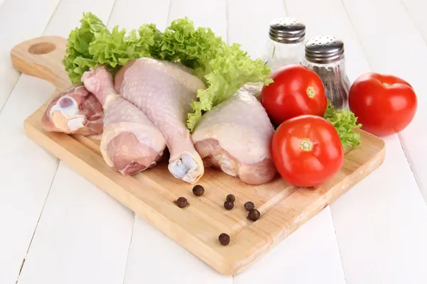 Raw chicken legs on wooden board on wooden table — Stock Photo, Image