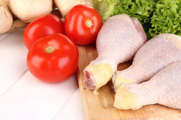 Pernas de frango cru na tábua de madeira de perto — Fotografia de Stock