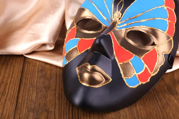 Masker op gouden stof op houten achtergrond — Stockfoto