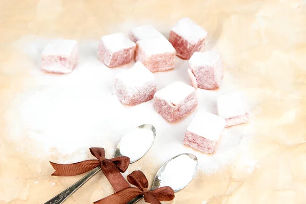 Tasty oriental sweets (Turkish delight) with powdered sugar, on brown background — Stock Photo, Image