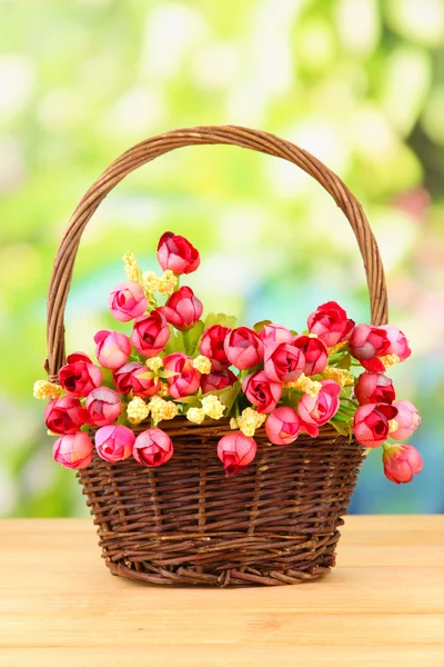 Bouquet of beautiful artificial flowers basket, on wooden table — Stock Photo, Image