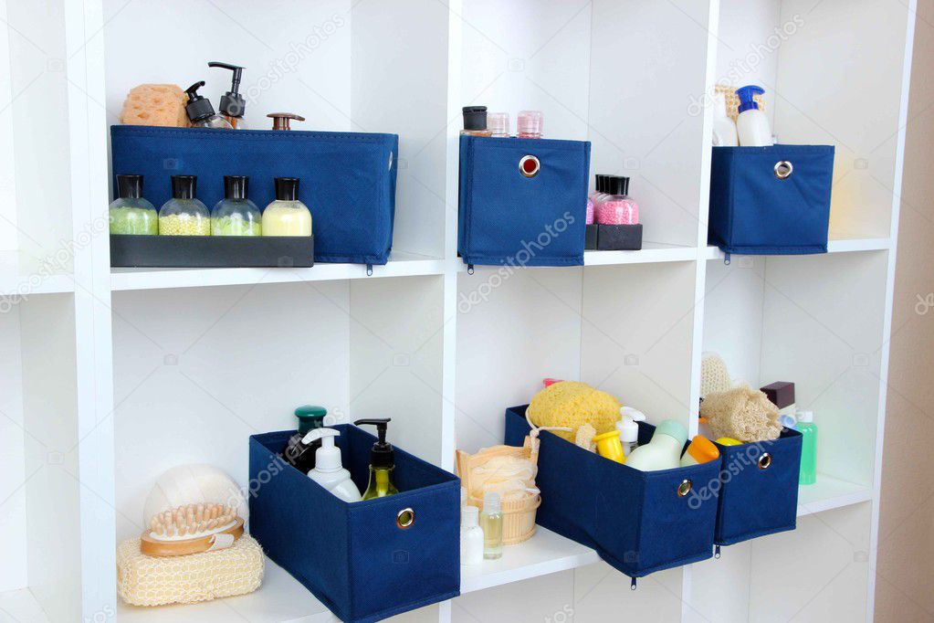 Blue textile boxes with cosmetic products for personal care in white shelves