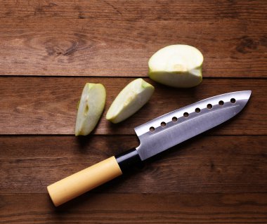 Mutfak bıçağı ve yeşil elma, ahşap arka planda.