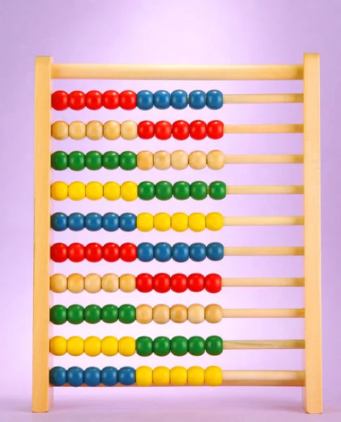 Abacus de brinquedo de madeira brilhante, no fundo roxo — Fotografia de Stock