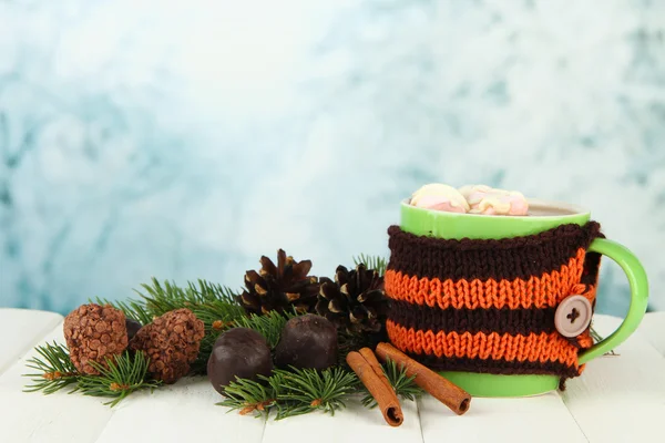 Cup of hot cacao with chocolates and fir branches on table on bright background — Stock Photo, Image