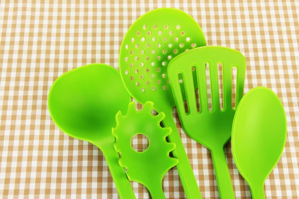 Plastic kitchen utensils on fabric background — Stock Photo, Image