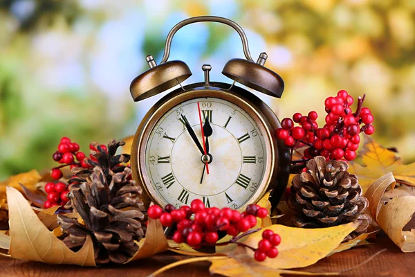 Alte Uhr auf Herbstblättern auf Holztisch vor natürlichem Hintergrund — Stockfoto