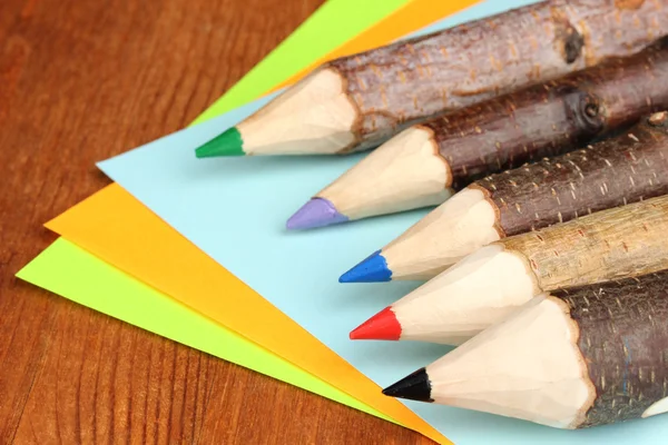 Colorful wooden pencils with sheets of paper — Stock Photo, Image