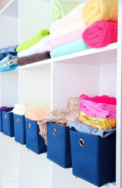 Caixas têxteis azuis com toalhas e roupas em prateleiras brancas — Fotografia de Stock