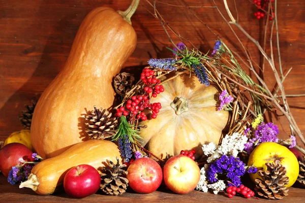 Composition automnale de pommes, citrouilles, fleurs et branches sèches sur table en bois sur fond en bois — Photo