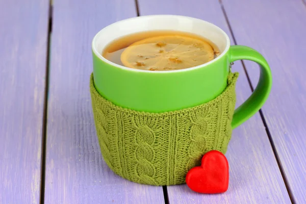 Cup with knitted thing on it on wooden table close up — Stock Photo, Image