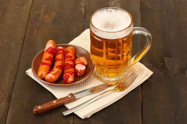 Cerveza y embutidos a la parrilla sobre fondo de madera — Foto de Stock