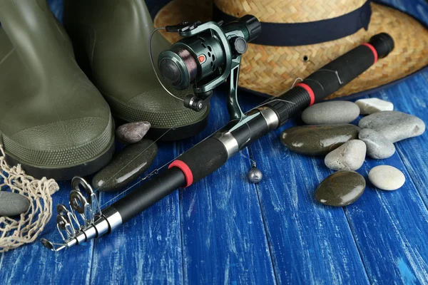 Fishing rod, gumboots and hat on table — Stock Photo, Image