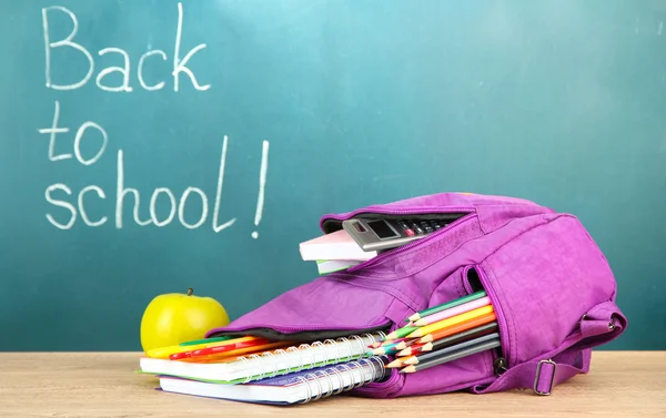 Mochila con útiles escolares en mesa de madera — Foto de Stock