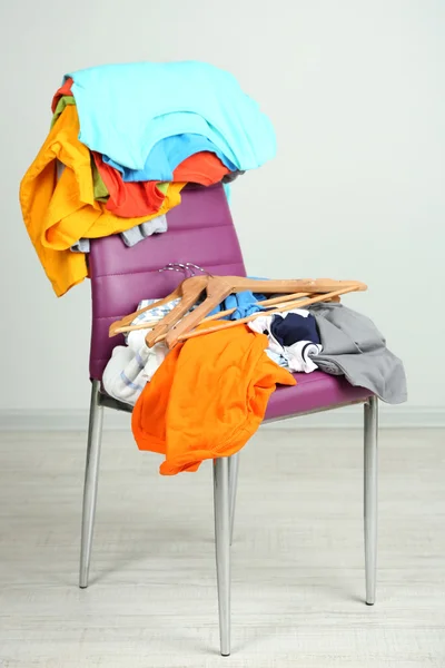 Heap of clothes on color chair, on gray background — Stock Photo, Image