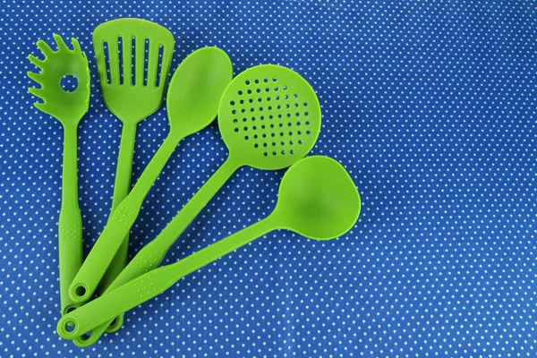 Plastic kitchen utensils on fabric background — Stock Photo, Image