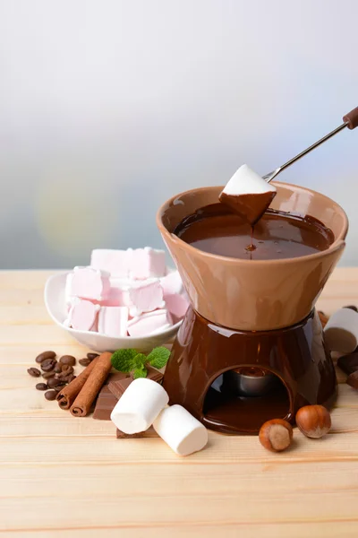 Chocolate fondue with marshmallow candies, on wooden table, on light background — Stock Photo, Image