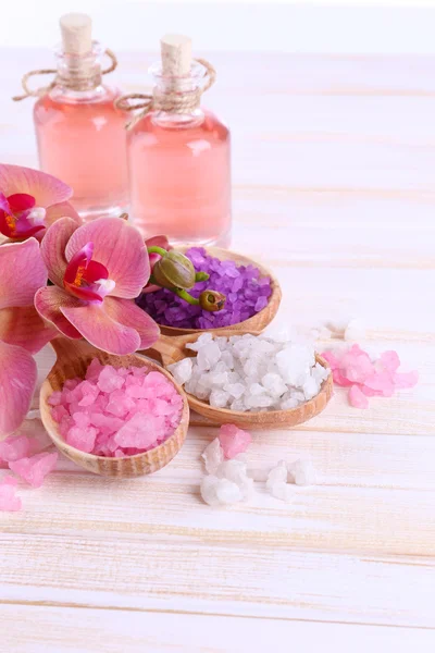 Still life with beautiful blooming orchid flower and wooden spoons with sea salt, on color wooden background — Stock Photo, Image