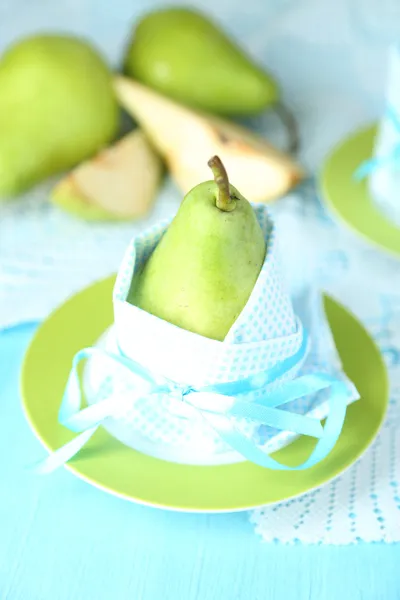 Poires dans les serviettes sur les assiettes sur la table en bois close-up — Photo