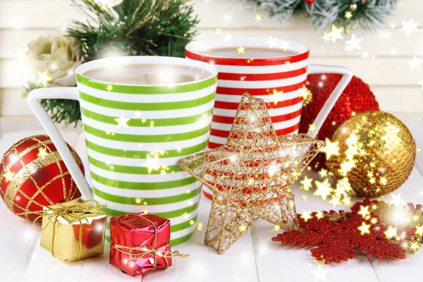 Cups of hot cacao with Christmas decorations on table on wooden background — Stock Photo, Image