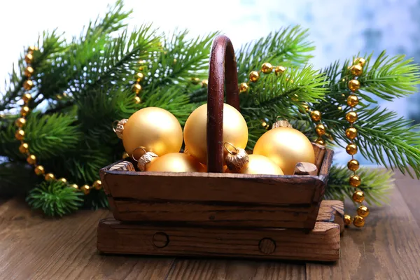 Composición con decoraciones navideñas en cesta, abeto sobre mesa de madera, sobre fondo claro —  Fotos de Stock