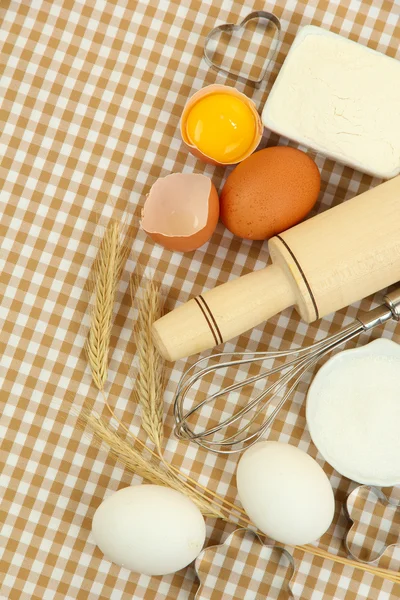 Kochkonzept. Grundlegende Backzutaten und Küchengeräte auf Tischdecken-Hintergrund — Stockfoto