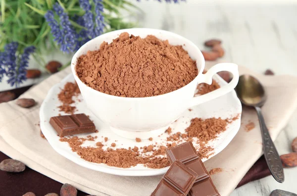 Poeder van de cacao in cup op servet op houten tafel — Stockfoto