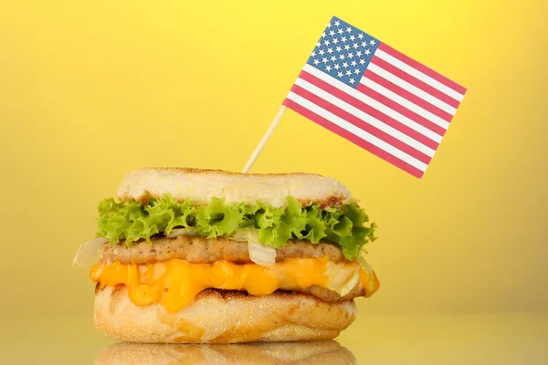 Sanduíche saboroso com bandeira americana, no fundo amarelo — Fotografia de Stock