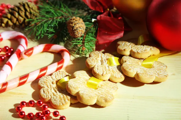 Cookies on ribbons with Christmas decorations on wooden table — Stock Photo, Image