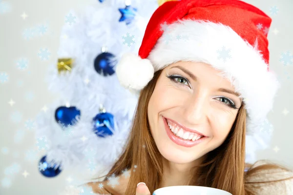 Vacker leende flicka nära julgran med kopp — Stockfoto
