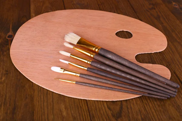 Wooden art palette and brushes on table close-up — Stock Photo, Image