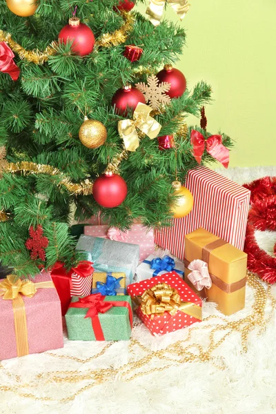 Decorated Christmas tree with gifts on green wall background — Stock Photo, Image