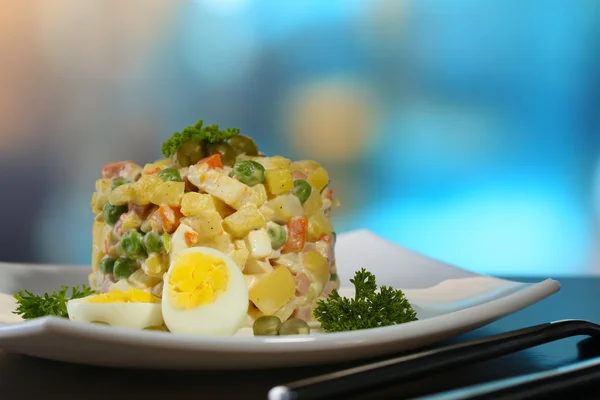 Russische traditionele salade olivier, op kleur servet, op houten tafel, op lichte achtergrond — Stockfoto