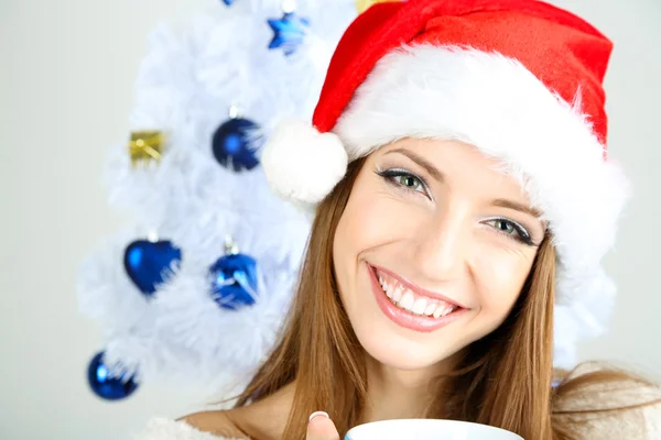 Mooi lachende meisje in de buurt van kerstboom met kop — Stockfoto