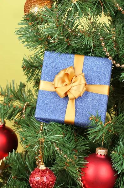 Regalo en el árbol de Navidad sobre fondo de color — Foto de Stock