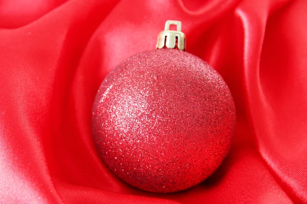 Beautiful Christmas ball on red satin cloth — Stock Photo, Image