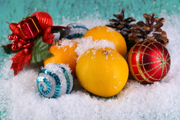 Tangerinas de Natal e brinquedos de Natal na mesa de madeira na neve — Fotografia de Stock